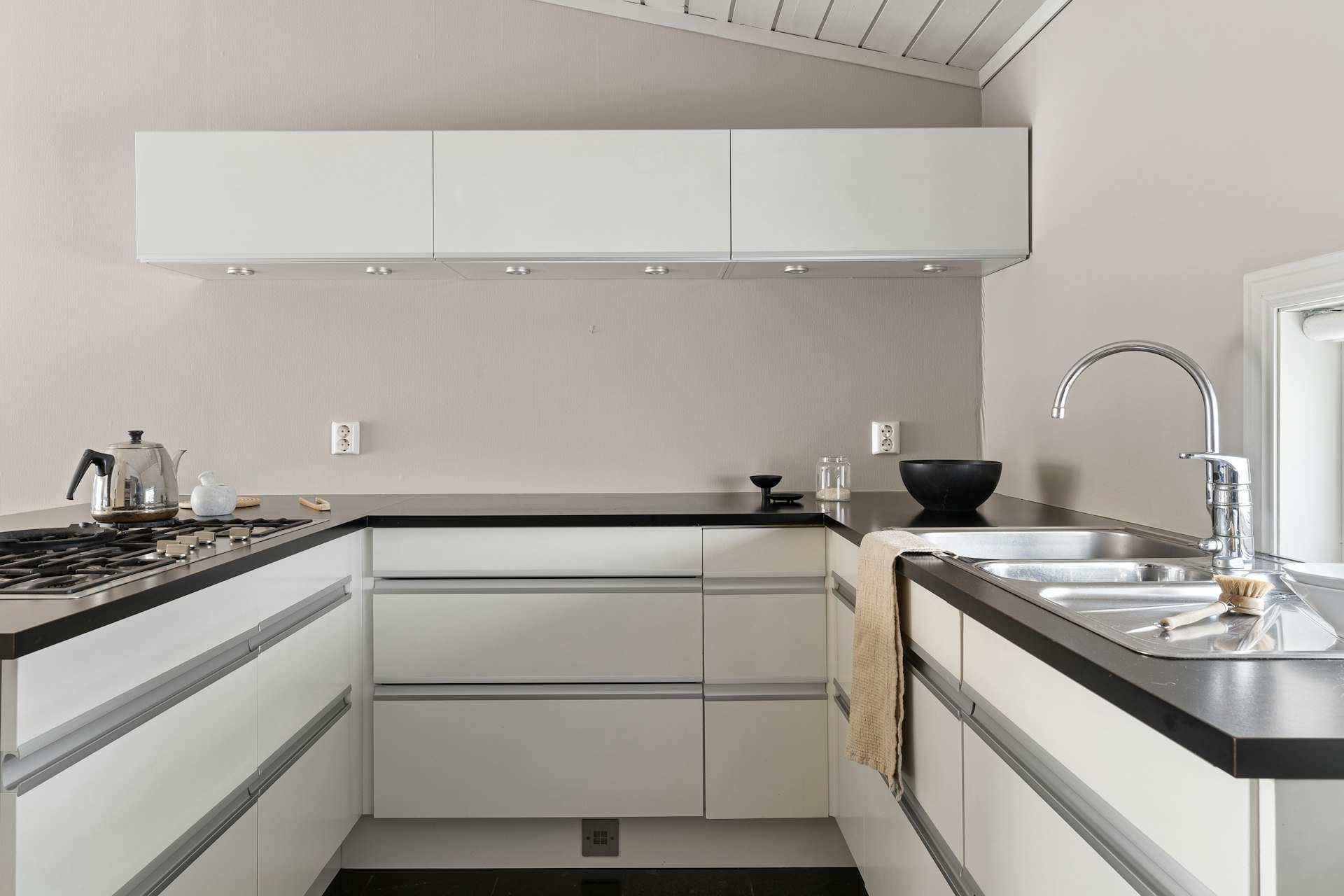 A kitchen with white cabinets and black counter tops